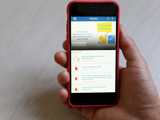 Foto de mano sosteniendo un teléfono celular en cuya pantalla aparece la aplicación Personas UC
