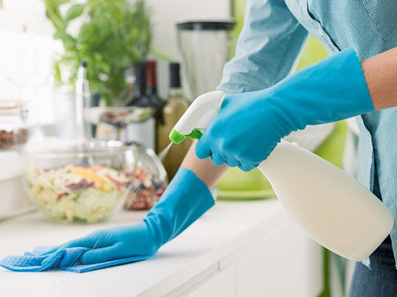 Se muestra persona limpiando una superficie de una mesa de cocina.