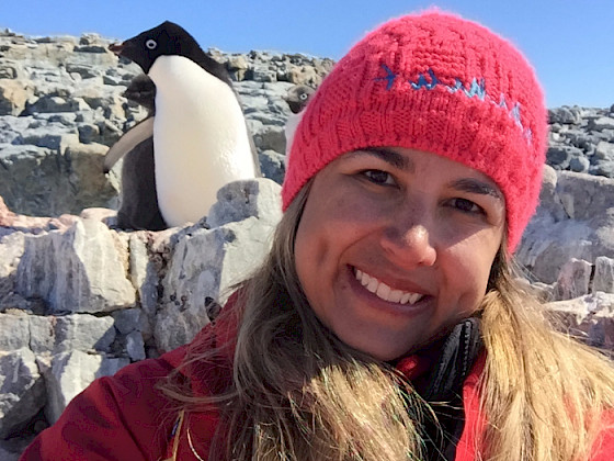 Imagen de profesora Juliana Vianna con ropa abrigada cerca de un pinguino