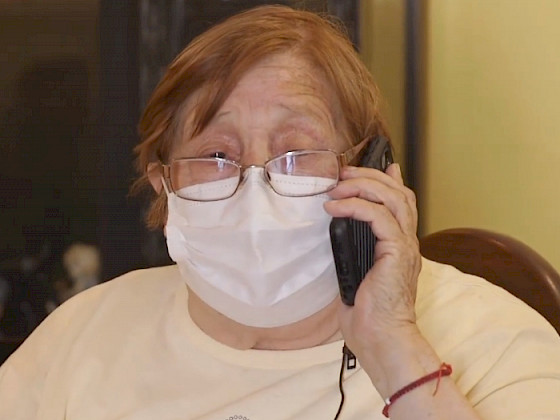 Mujer mayor con mascarilla hablando por celular.