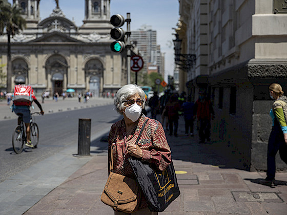 Persona mayor con mascarilla detenida en la calle y de fondo se ve la Catedral Metropolitana