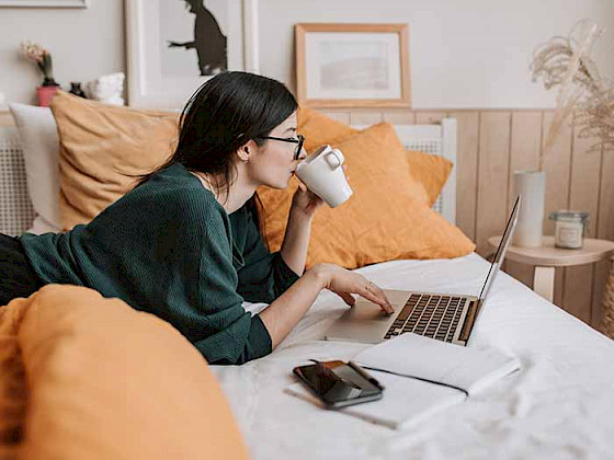 Imagen de mujer bebiendo café y estudiante frente a su computador.