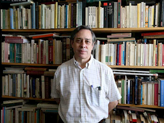 Retrato de Claudio Rolle frente a su biblioteca personal.