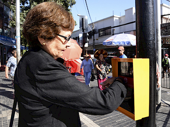 Anciana con un braselete en el brazo extiende la luz roja en un semáforo gracias a una tecnología que este último porta ensamblada.