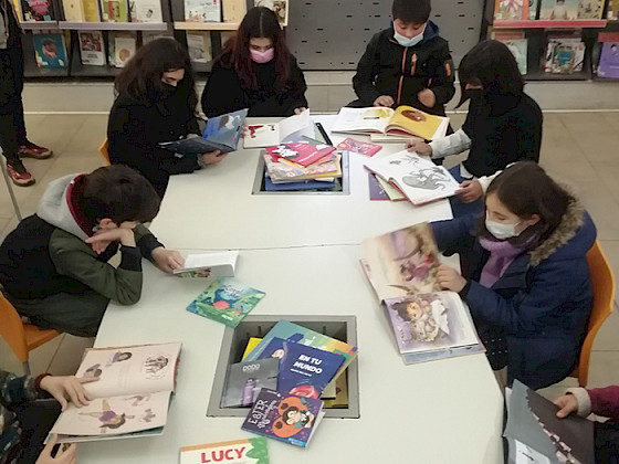 Niñas y niños evaluando libros infantiles en la Biblioteca de Santiago.