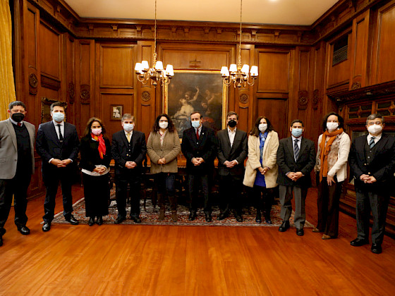 grupo de hombres y mujeres de pie, con mascarilla y ropa formal abrigada