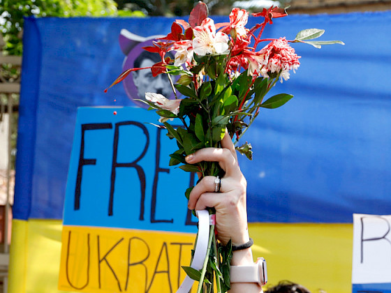 a person holding a bouquet of flowers in front of a sign that says free ukraine