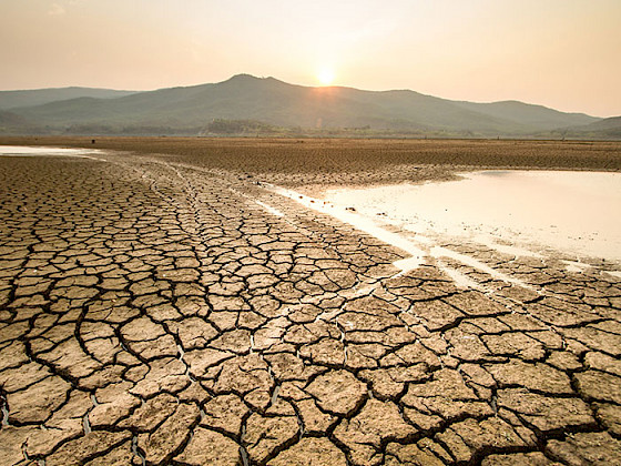 Tierra agrietada y un lago con agua escasa.