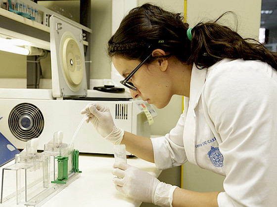 Científica manipulando una pipeta en un laboratorio.