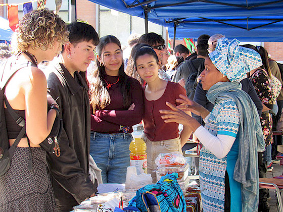 Un grupo de jóvenes escuchan atentos a una mujer que viste un traje africano.