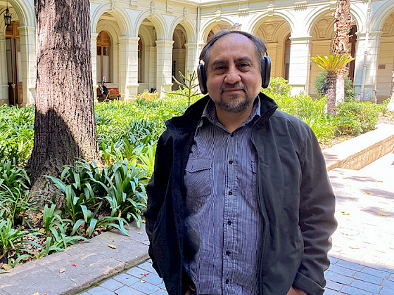El profesor Rodrigo Cádiz de pie llevando sus audífonos puestos, en un patio de Casa Central de la Universidad Católica.