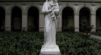 Escultura blanca de la Virgen María con el niño en brazos.