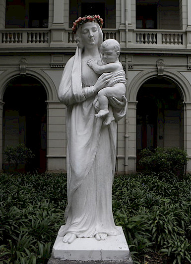 Escultura blanca de la Virgen María con el niño en brazos.