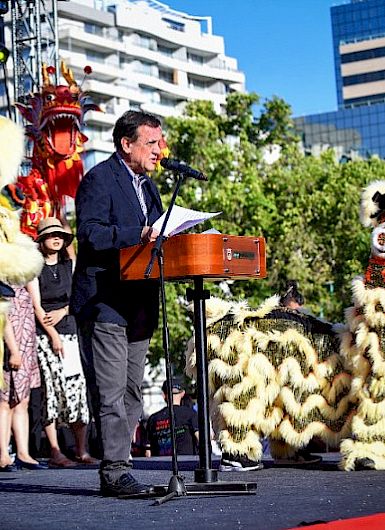 UC Chile President Ignacio Sánchez speaking on a stage next to two figures representing a lion during the celebration of the Chinese New Year.