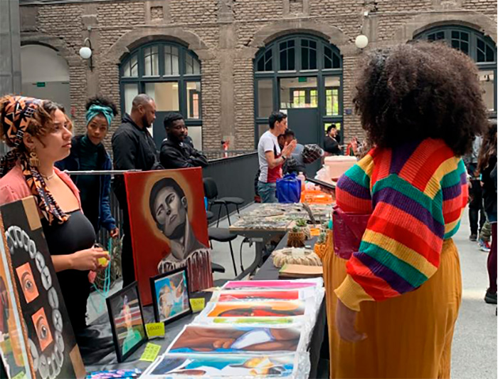 Mujeres junto a un stand que muestra dibujos de la cultura afro. 