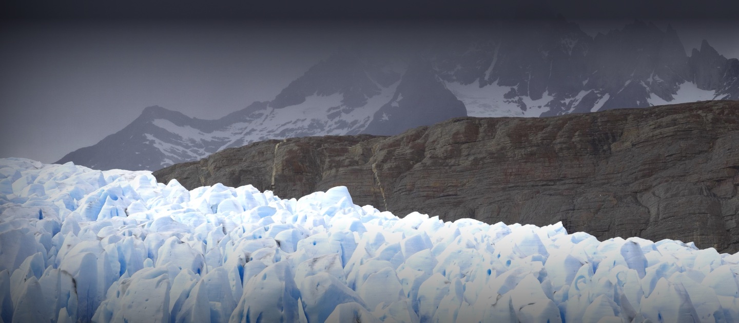 Imagen de un glaciar en primer plano y montañas de fondo