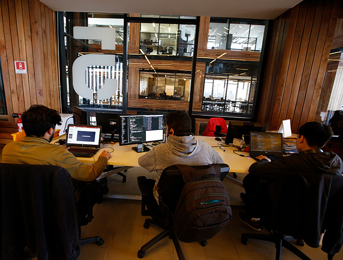 Jóvenes trabajando en sus computadores en uno de los laboratorios del Centro de Innovación UC.