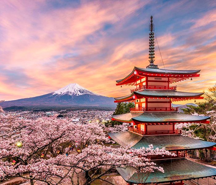 Pagoda junto a un cerezo en flor y el monte Fuji de fondo