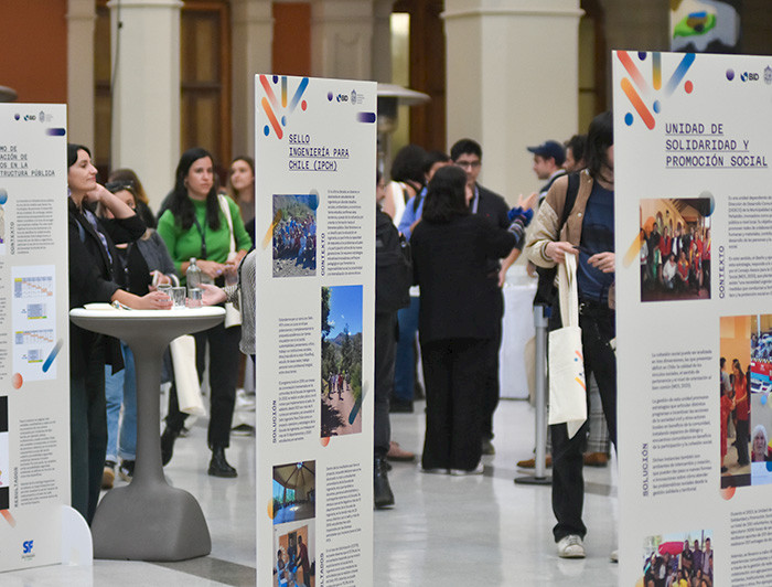 Exhibición con paneles que muestran las iniciativas de LIP UC y personas de fondo.