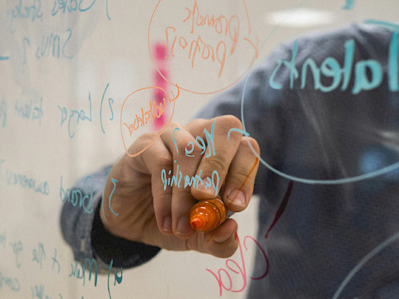 Persona escribe ideas en un vidrio con un làpiz de color.