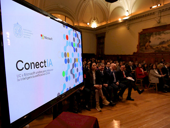 Screen where you can see ConectIA and the public in the background in the UC Chile Hall of Honor.