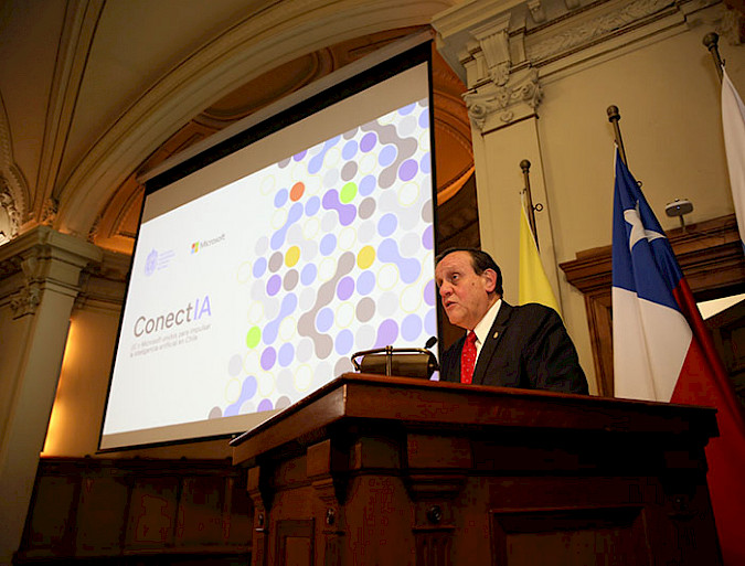 UC Chile President Ignacio Sánchez speaking from a podium, along with the presentation of ConectIA.