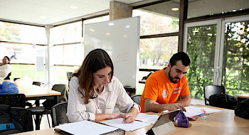 Dos estudiantes sentados frente a una mesa leyendo