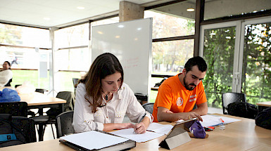 Dos estudiantes sentados frente a una mesa leyendo