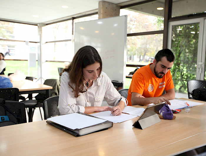 Dos estudiantes sentados frente a una mesa leyendo