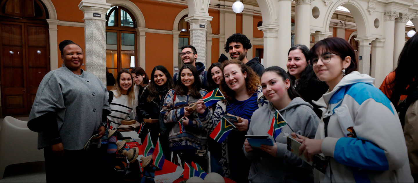 Estudiantes posan en un stand sosteniendo banderas de Sudáfrica.