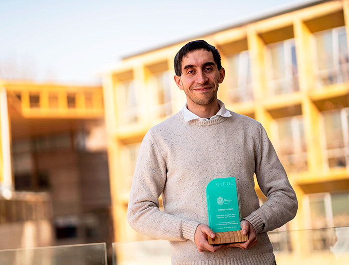 Benjamín Diethelm sosteniendo su premio, se ven fachadas de edificios al fondo.