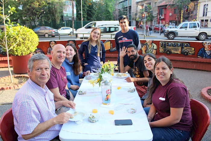 Personas comen sentadas en una mesa en la calle gracias a una iniciativa del proyecto Rostros.