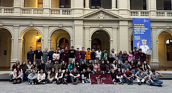 Grupo de 50 jóvenes de pie con una bandera en sus manos.