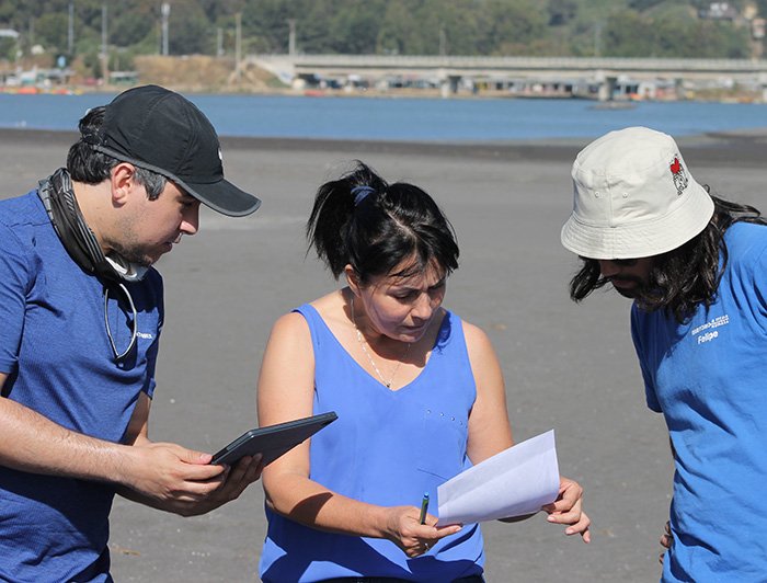 Profesora Carolina Martínez trabajando en terreno con dos investigadores.