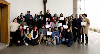 Grupo de Personas de pie, con diplomas en la mano, y un crucifijo en la muralla de atrás