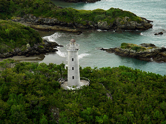 Lighthouse surrounded by lush greenery on the coast of Tantauco Park, Chiloé Island.