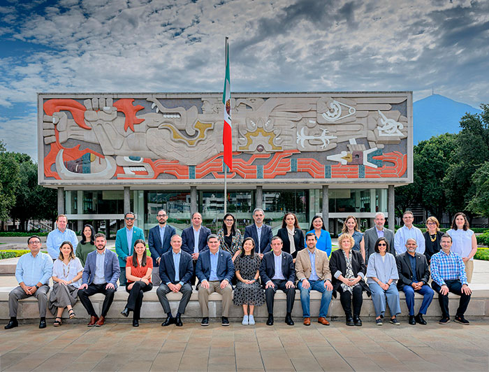 Participantes en cumbre de La Tríada, fachada de un edificio del Tec de Monterrey de fondo