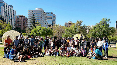 Group of international students and staff gathered outdoors at UC Chile, with city buildings and trees in the background.