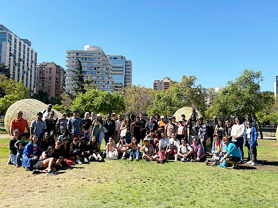 Group of international students and staff gathered outdoors at UC Chile, with city buildings and trees in the background.