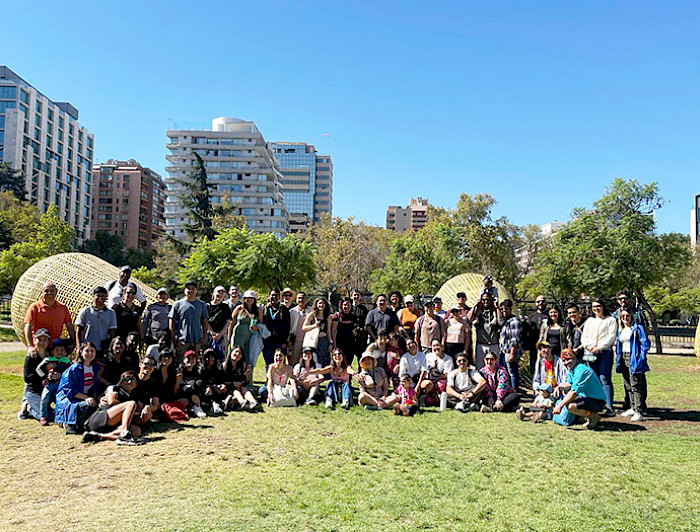 Group of international students and staff gathered outdoors at UC Chile, with city buildings and trees in the background.