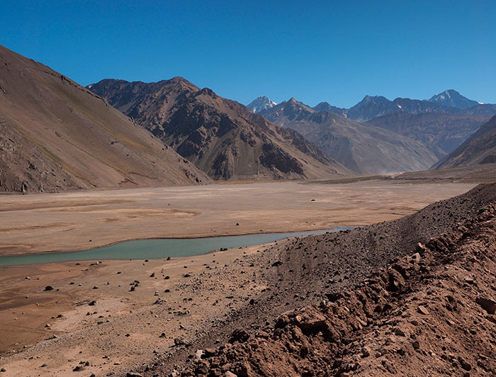 Un pequeño curso de agua entre medio de cerros áridos. 