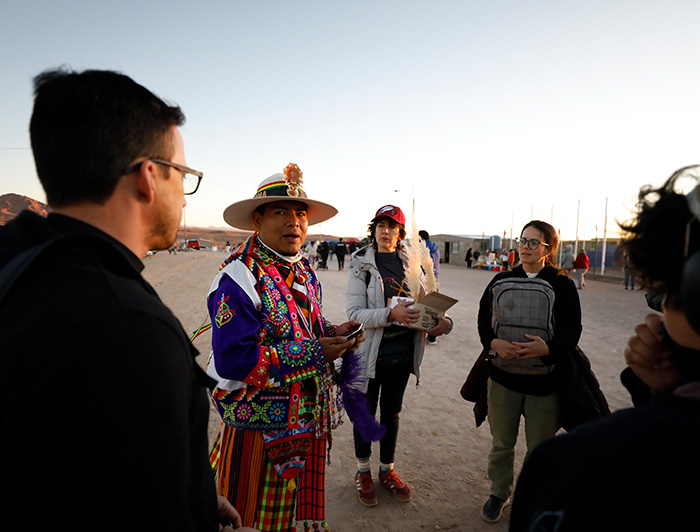 Estudiantes y docentes de la UC conversando con un bailarín de la fiesta de Ayquina.