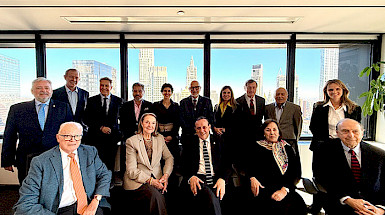 Group of board members from Friends UC gathered in a formal meeting room with a cityscape visible through the windows.