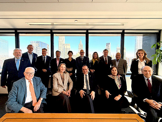 Group of board members from Friends UC gathered in a formal meeting room with a cityscape visible through the windows.