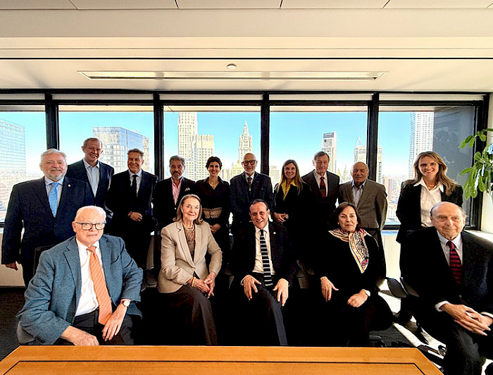 Group of board members from Friends UC gathered in a formal meeting room with a cityscape visible through the windows.