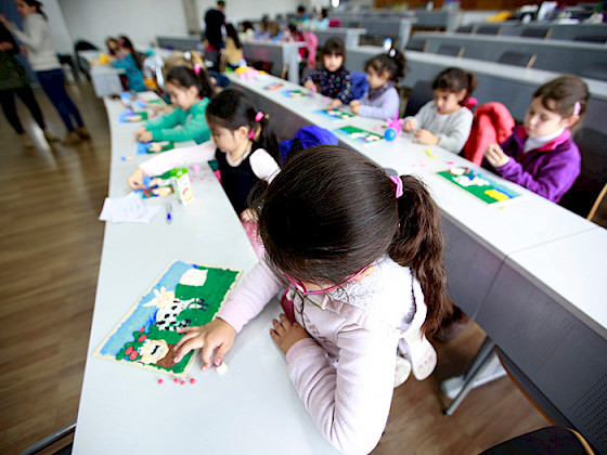 Niñas y niños haciendo trabajos de artes plásticas en una sala.