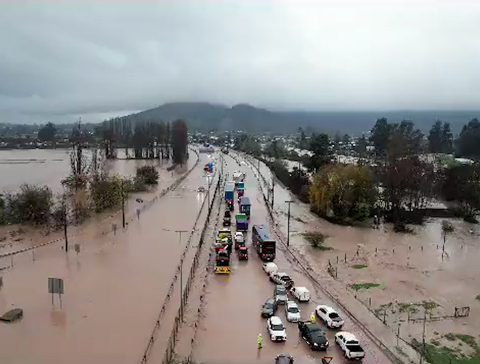 Vista aérea de una autopista y zona completamente inundada, y vehículos sobre el agua.