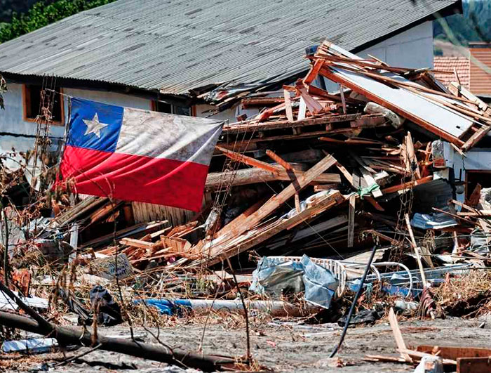 Bandera chilena junto a escombros tras un terremoto