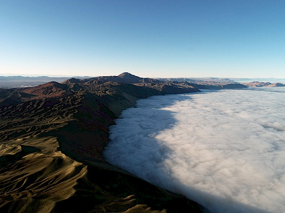 Thick fog stretching across a mountainous region in the Atacama Desert, viewed from above.