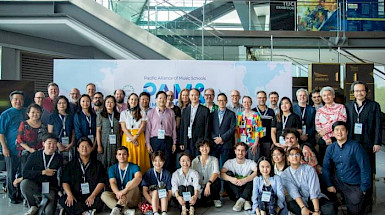 A diverse group of music educators, students, and professionals pose for a group photo at the Pacific Alliance of Music Schools event in a modern conference setting. (Photo credit: IMUC-PAMS)